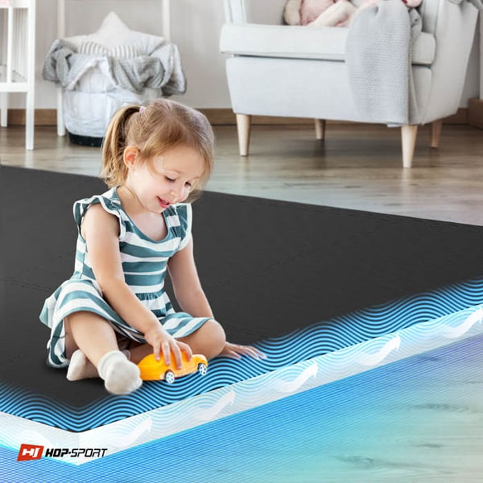 Bambino seduto su un tappetino puzzle nero Hop-Sport 1 cm 8 pezzi