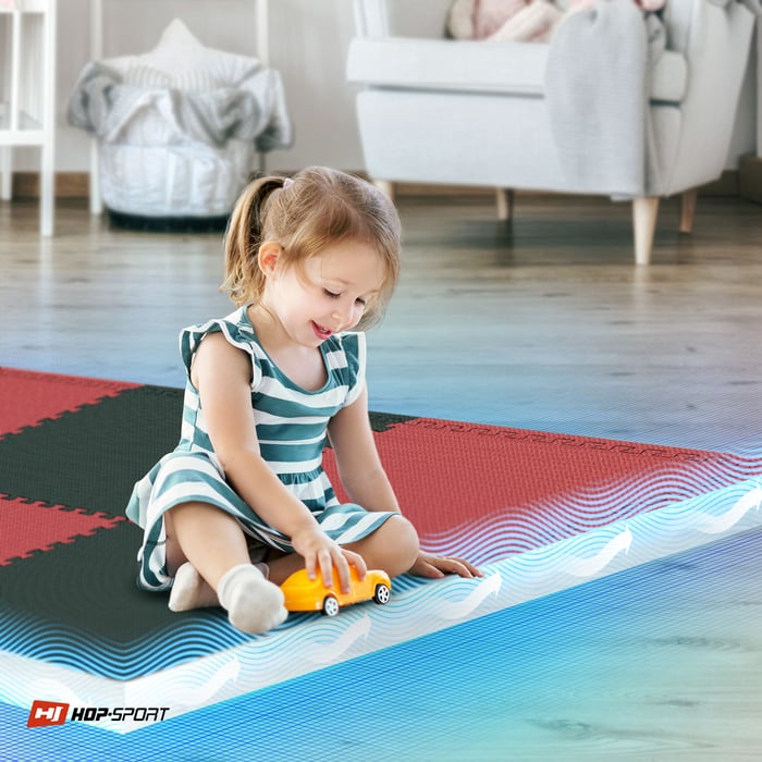 Bambino seduto su un tappetino puzzle nero-rosso Hop-Sport
