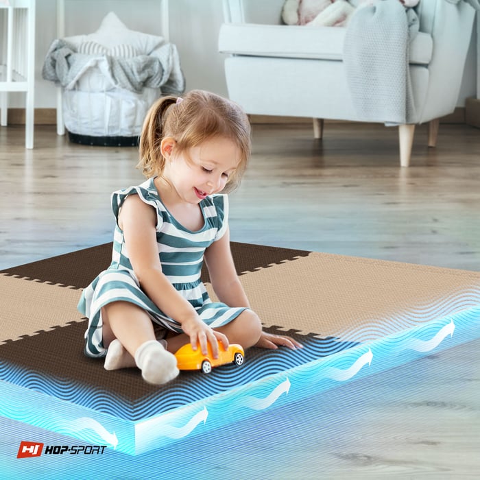 Bambino seduto su un tappetino puzzle Hop-Sport marrone-beige