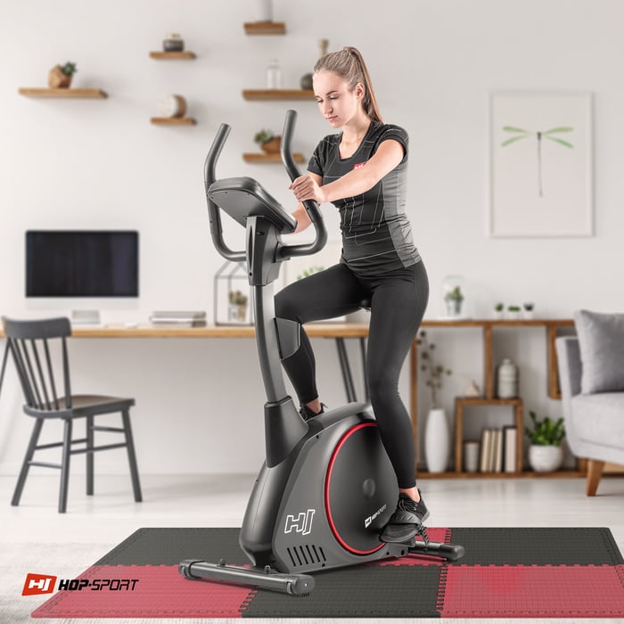 Ragazza che si allena su attrezzature fitness posizionate su un tappetino puzzle nero-rosso Hop-sport