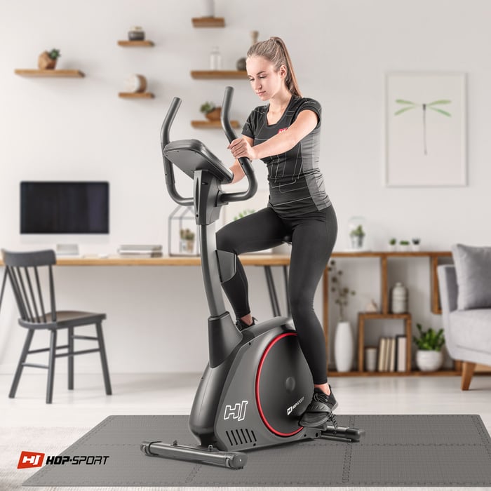 Ragazza che si allena su attrezzature fitness posizionate su un tappetino puzzle grigio Hop-sport