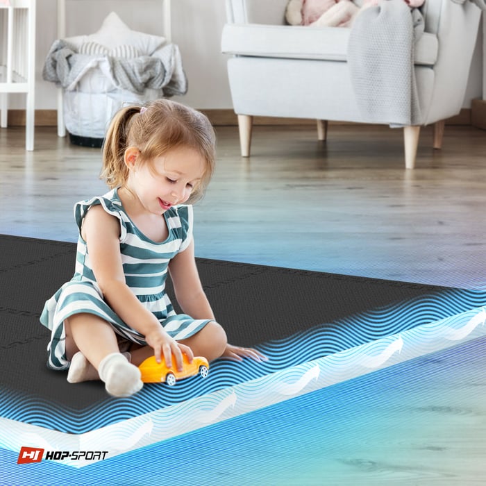 Bambino seduto su un tappetino puzzle nero Hop-Sport 1 cm 6 pezzi