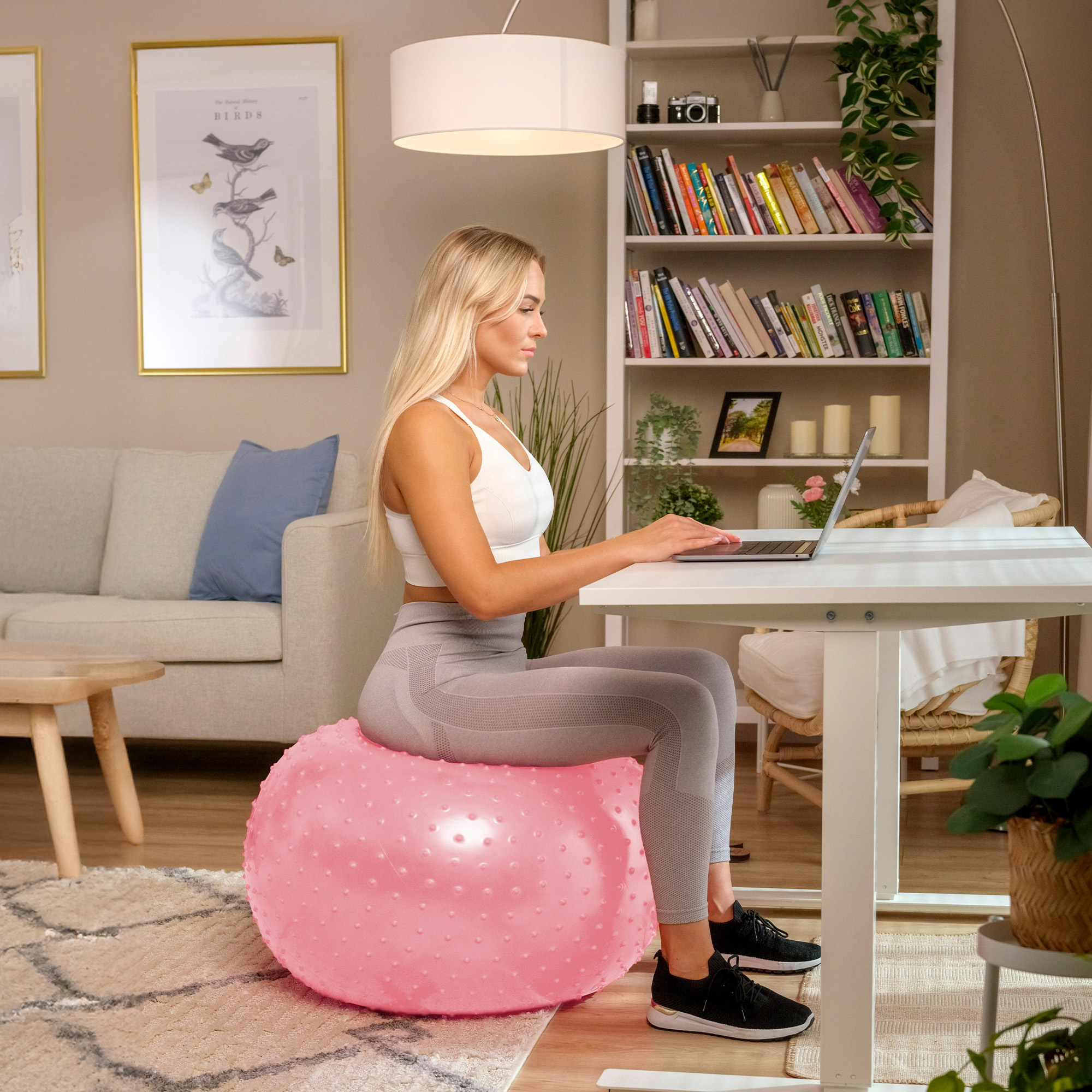 Donna usa la palla ginnica rosa con rilievi per lavorare alla scrivania