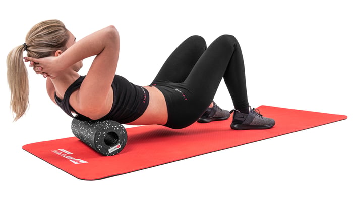 Donna che massaggia i muscoli della schiena con un rullo lungo 33cm nero a pois bianchi