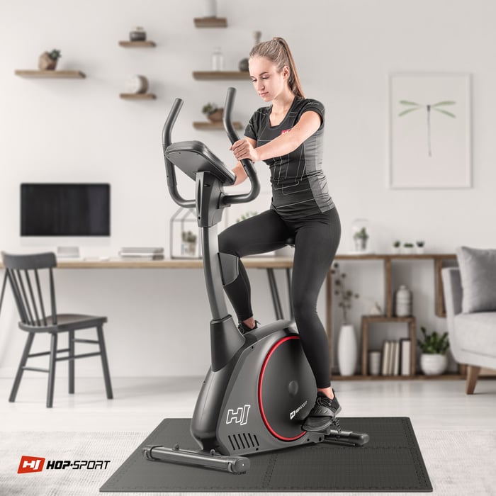 Ragazza che si allena su attrezzature fitness su un tappetino puzzle nero Hop-sport